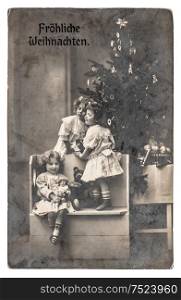Happy kids with Christmas tree, gifts and vintage toys. Antique sepia picture with original film grain and blur
