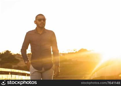 Happy latin man walking and enjoying the sunset with a natural landscape view. Warm natural light.