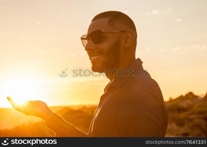 Happy latin man walking and enjoying the sunset with a natural landscape view. Warm natural light.