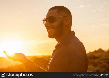 Happy latin man walking and enjoying the sunset with a natural landscape view. Warm natural light.