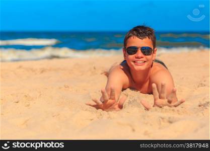 Happy laughing boy of thirteen on the sea beach shows the hands in the sand. Shallow depth of field, focus on hands and face