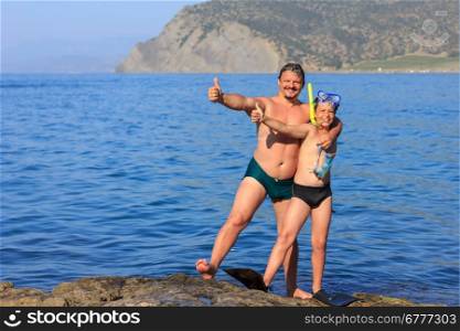 happy laughing father and son with a scuba mask on the sea beach