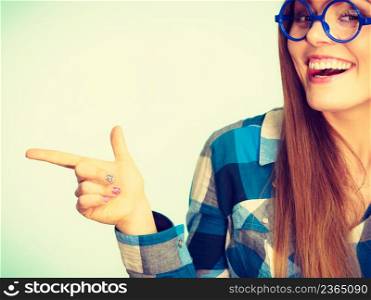 Happy laughing in checked shirt pointing at something with finger. Studio shot on blue background. Happy woman pointing at something with finger
