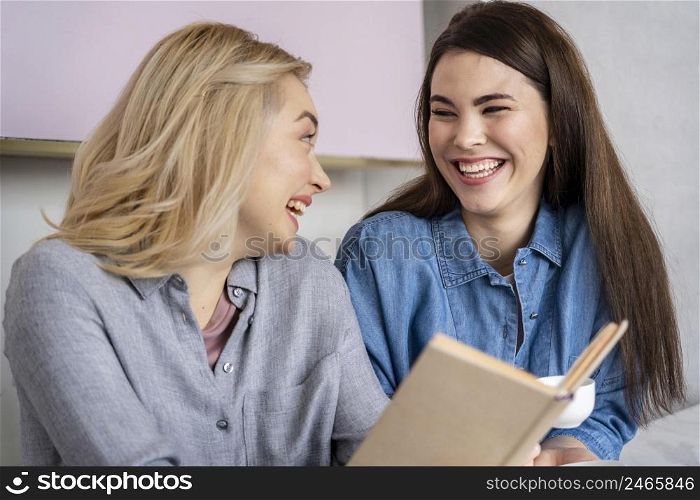 happy laughing women having coffee reading book