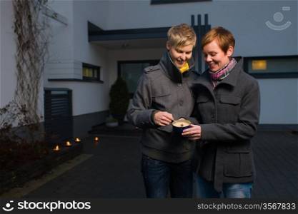 Happy lesbian couple light a candle on front yard of the house