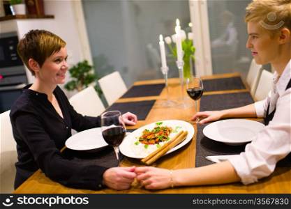Happy lesbian couple sits on a dinner table and having good time together