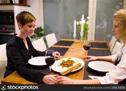 Happy lesbian couple sits on a dinner table and having good time together
