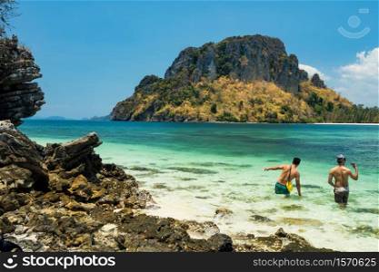 Happy LGBT Gay couple walk on crystal turquoise blue sea at island Thale Waek, the unseen Krabi in summer vacation in southern of Thailand. Famous travel destination of beautiful beach.