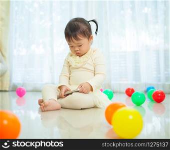 Happy little asian girl using mobile phone in the home