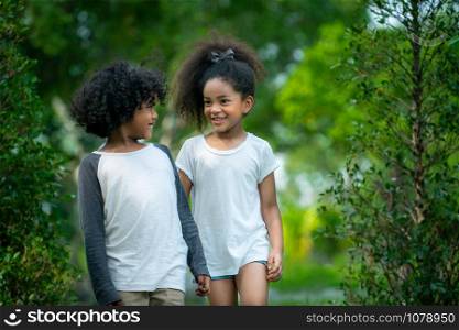 Happy little boy and girl in the park. Two African American children together in the garden.