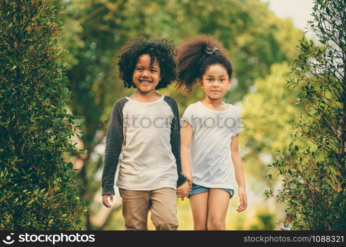 Happy little boy and girl in the park. Two African American children together in the garden.