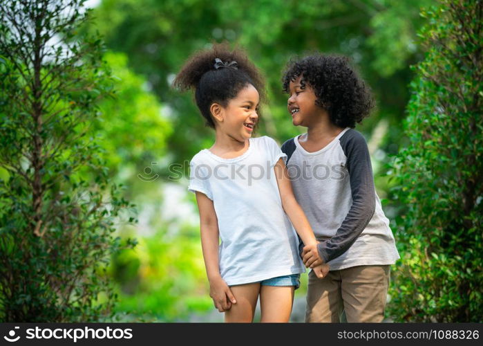 Happy little boy and girl in the park. Two African American children together in the garden.