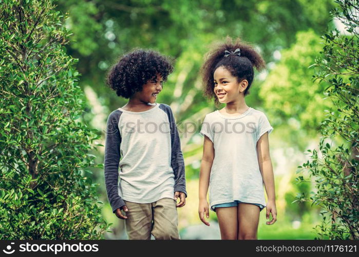 Happy little boy and girl in the park. Two African American children together in the garden.