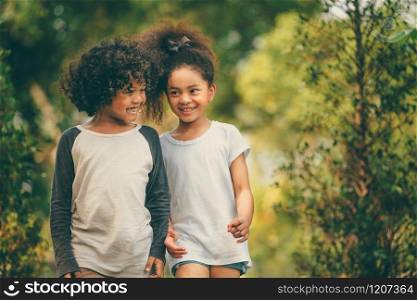 Happy little boy and girl in the park. Two African American children together in the garden.. Happy little boy and girl in the park.