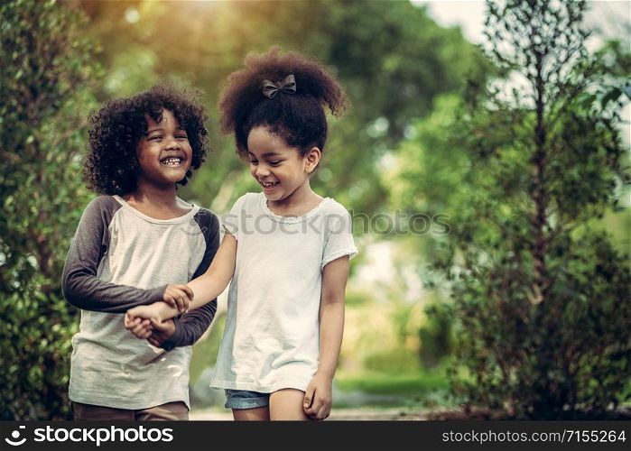 Happy little boy and girl in the park. Two African American children together in the garden.