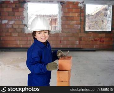 Happy little boy bricklayer building a house