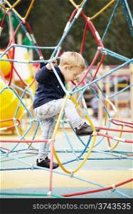 Happy little boy climbing on playground equipment as he enjoys the adventure and exercise