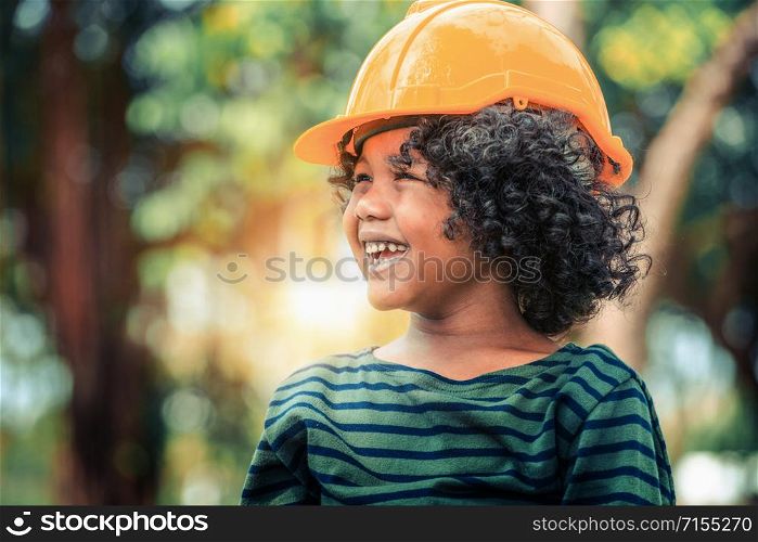 Happy little boy engineer wearing yellow safety helmet hard hat and laughing with happiness. Education and learning concept.