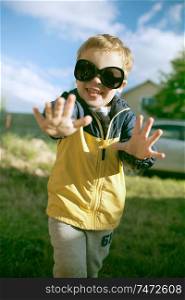 Happy little boy having fun in big sunglasses outdoor