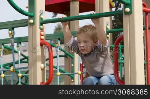 Happy little boy having fun on playground equipment and then something attracts his attention.