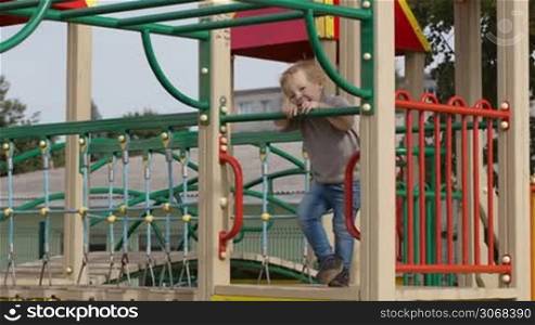 Happy little boy having fun on playground equipment and then something attracts his attention.
