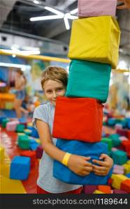 Happy little boy playing with soft cubes, playground in entertainment center. Play area indoors, playroom