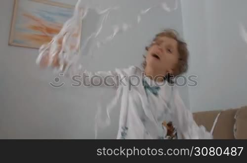 Happy little boy playing with white confetti. Playful child having fun at paper party