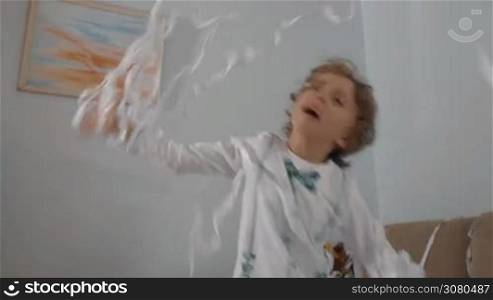 Happy little boy playing with white confetti. Playful child having fun at paper party