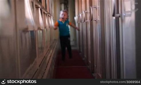 Happy little boy running along the train hallway
