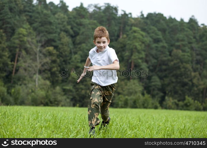 Happy Little boy running on the meadow in summer day