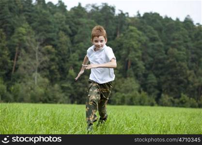 Happy Little boy running on the meadow in summer day