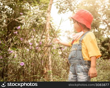 Happy little child girl enjoying flowers in the park on a sunny day.