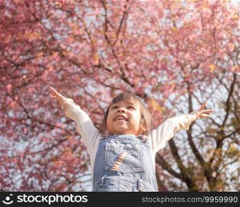 Happy little child girl enjoying with nature in the park on sunshine day in springtime.