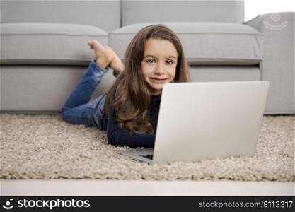 Happy little girl at home working with a laptop
