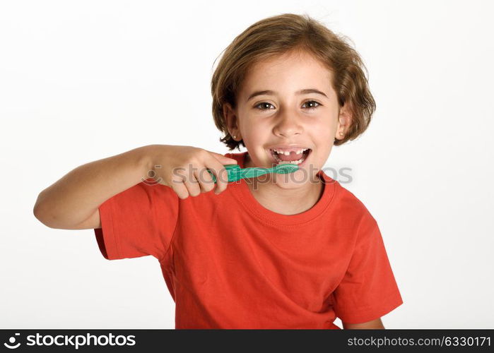 Happy little girl brushing her teeth with a toothbrush isolated on white background. Studio shot.