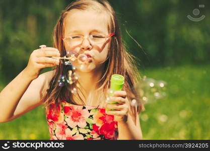 Happy little girl child blowing bubbles outdoor.. Smiling little girl child blowing soap bubbles outdoor. Joyful kid having fun in park. Happy and carefree childhood. Instagram filtered.