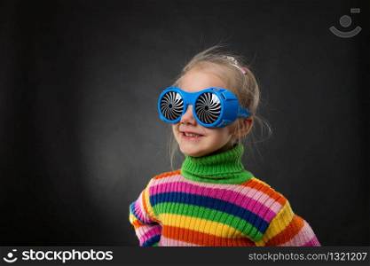 Happy little girl in party glasses on grey