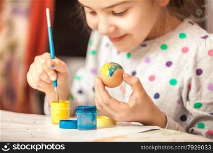 Happy little girl painting easter egg