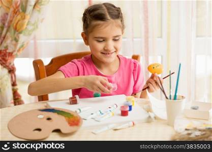 Happy little girl painting eggs for Easter