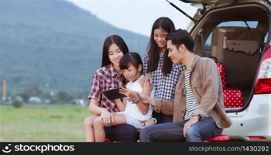 happy little girl playing ukulele with asian family sitting in the car for enjoying road trip and summer vacation,soft focus