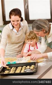 Happy little girl rolling out dough with mum and grandmother