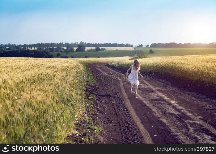 happy little girl running on a dirt road in the fields. Ukrainian landscape