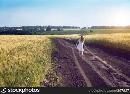 happy little girl running on a dirt road in the fields. Ukrainian landscape