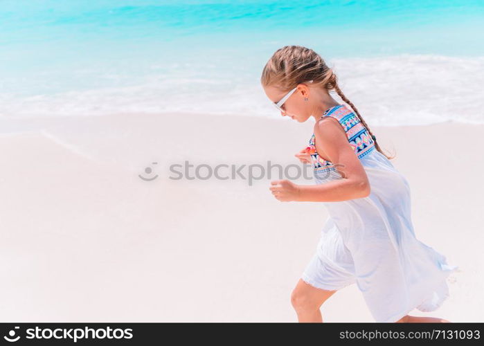 Happy little girl running on the beach. Adorable little girl at beach during summer vacation