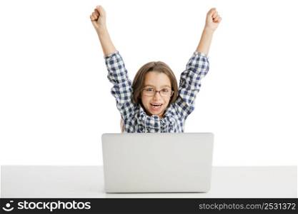 Happy little girl sitting on a desk and working with a laptop