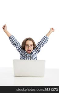 Happy little girl sitting on a desk and working with a laptop