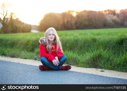 Happy little girl sitting on the road and smiling. travel with kid, France