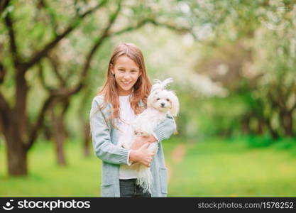 Happy little girl walk with a dog in the park. Little smiling girl playing and hugging puppy in the park