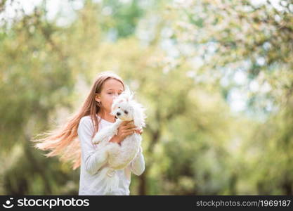 Happy little girl with a dog in the park. Little smiling girl playing and hugging puppy in the park