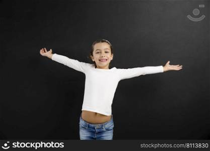 Happy little girl with arms open in front of a blackboard